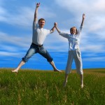 jumping couple in field under clouds