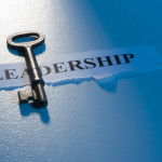 A key laying on a piece of paper with the word "leadership" on it.